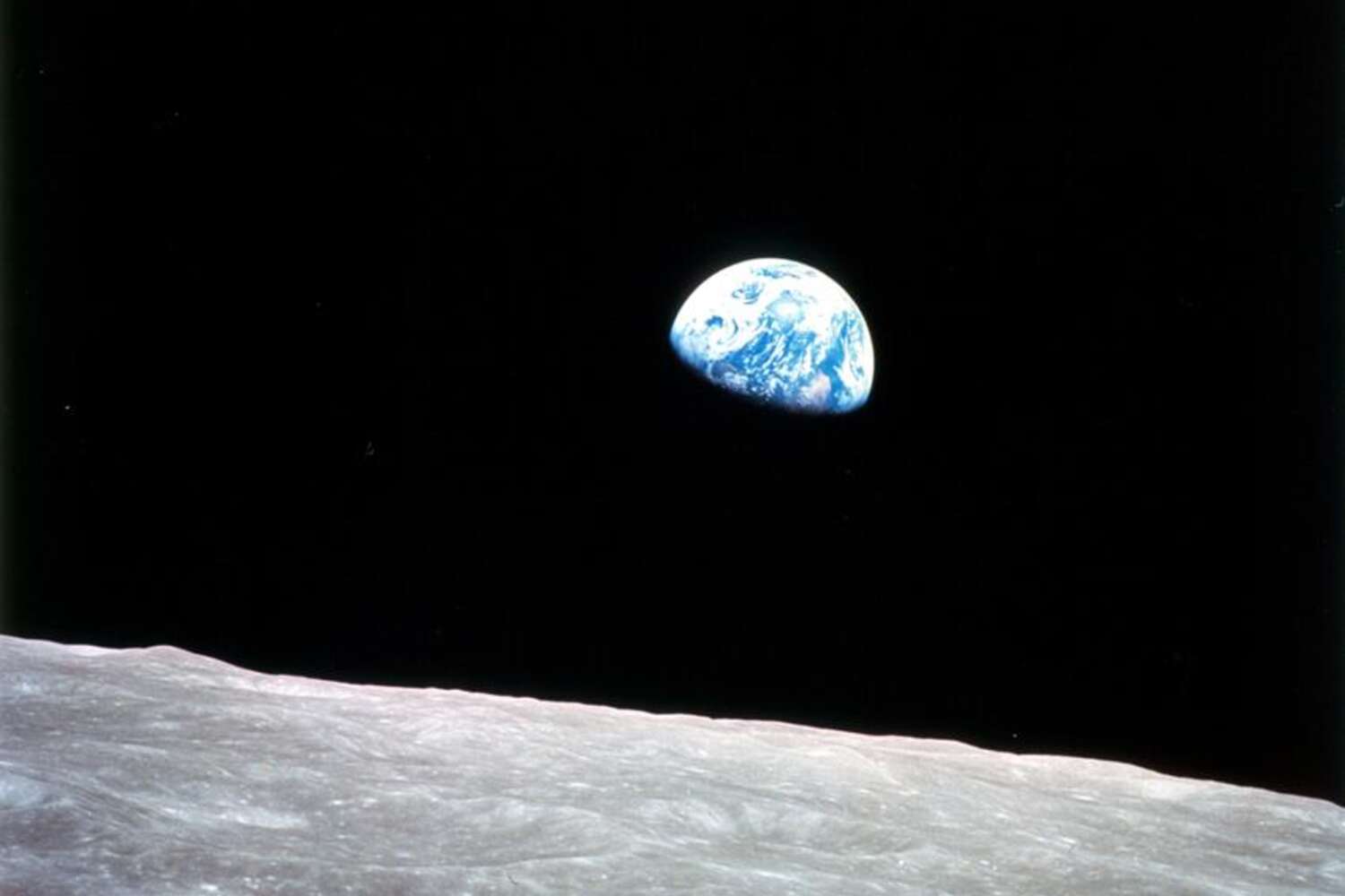 The Earth is seen rising above the lunar landscape in a photo taken from the Apollo 8 spacecraft.