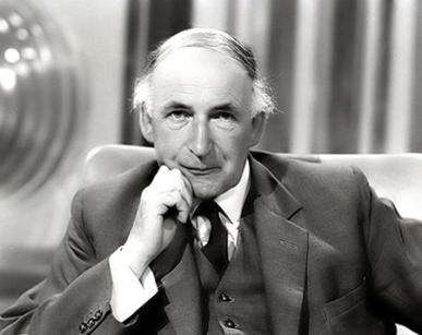 Black and white head and shoulders shot of Sir Bernard Lovell as an older man. He's sitting down, looking directly into the camera, not smiling, with his chin resting on his right hand. He's wearing a medium colour jacket and waistcoat, dark colour tie and white shirt.
