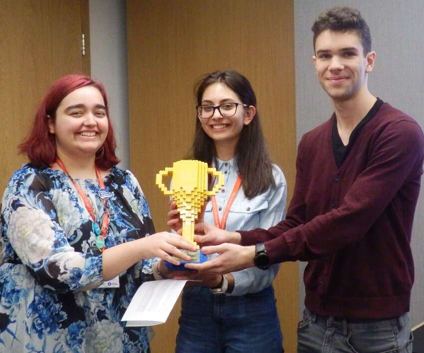 Dimona Videnlieva, Merian Alit, Toma Kolev hold up an award cup made out of lego.
