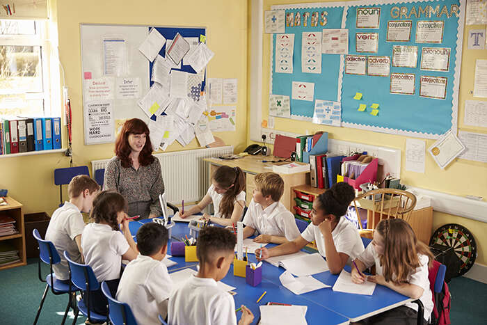 A teacher and her young students around a table in the classroom
