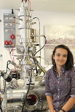 Maddison Coke, Senior Experimental Officer, University of Manchester, smiling next to physics equipment