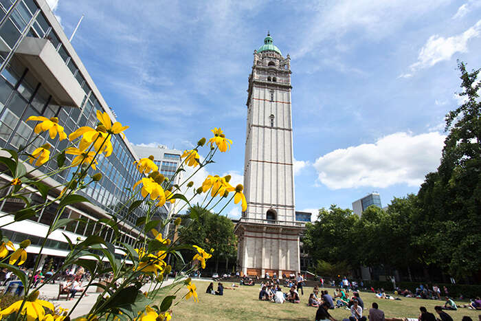 A tower in the background on the campus of Imperial College London, with students in the foreground