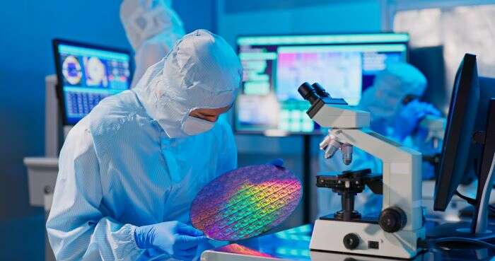 A lab technician with a colourful, circular semiconductor wafer