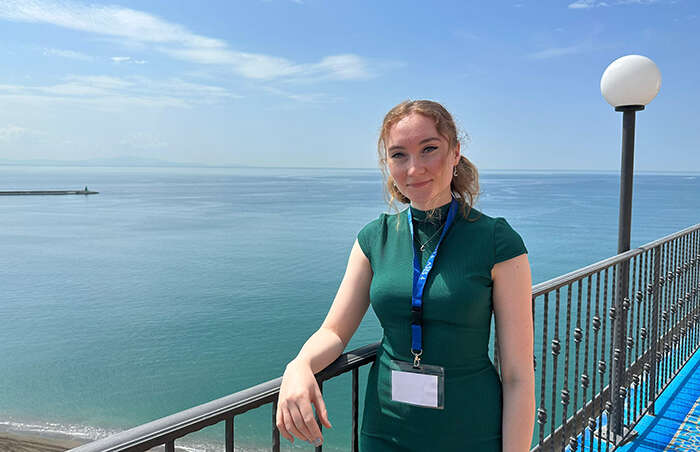 A portrait of astrophysicist Alix Freckelton on a pier with the blue sea in the background