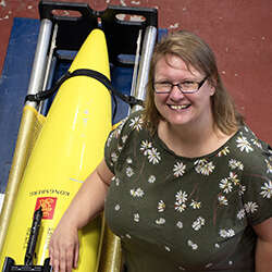 Clare Johnson, Oceanographer, Scottish Association for Marine Science, standing next to diving equipment
