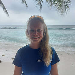 Jessica Savage, PhD Researcher in Marine Science on a beach smiling